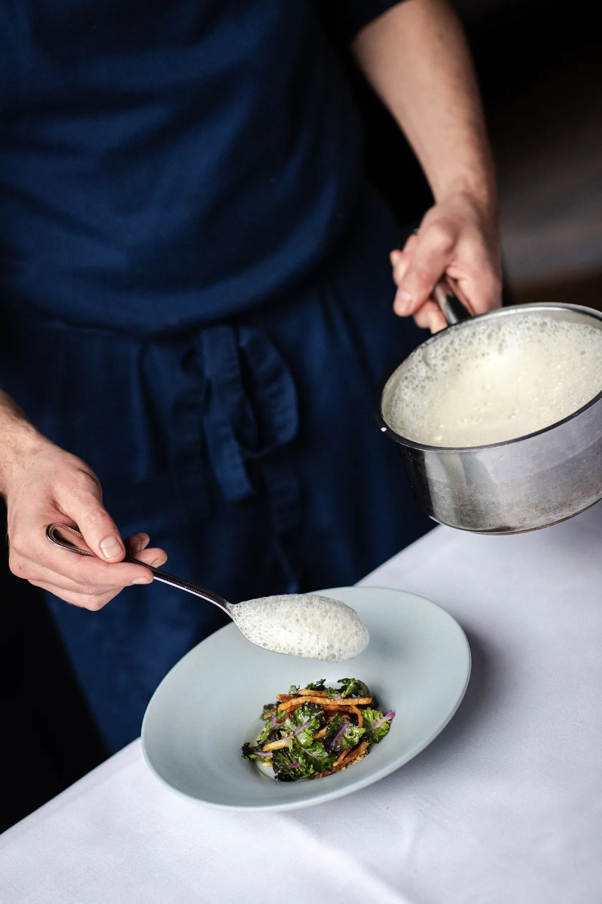 Le chef dresse un plat dans la cuisine de De Matroos en het Meisje